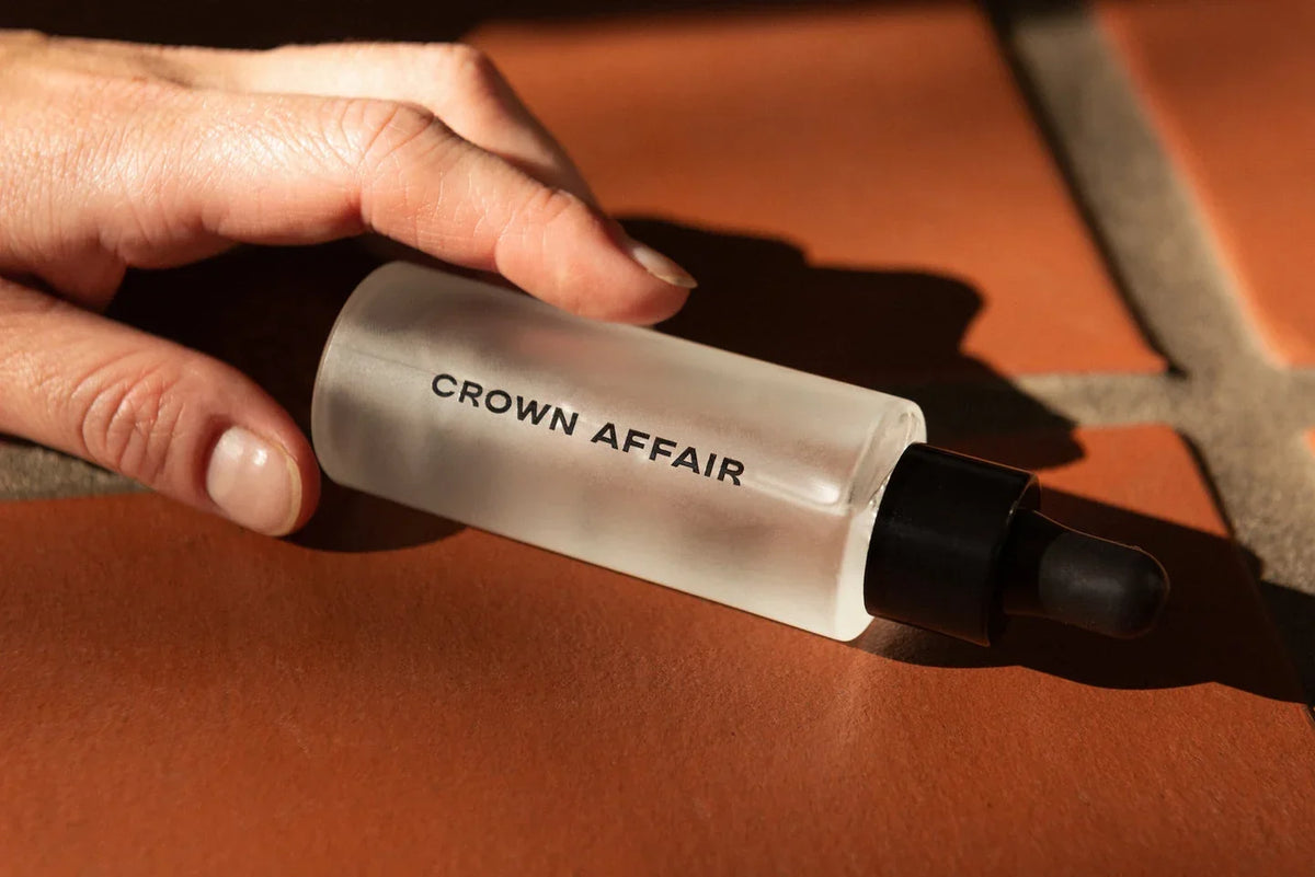 A hand holding a haircare bottle in warm light